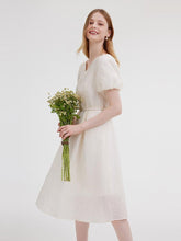 A lady with flowers wears a white babydoll dress.